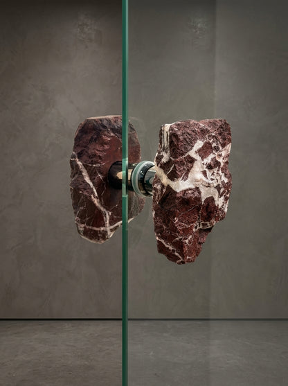Close-up of brecciated jasper glass door pull showing white quartz veining and stainless steel standoff