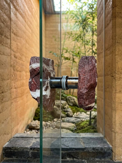Brecciated jasper raw stone back-to-back pull mounted on a frameless glass door