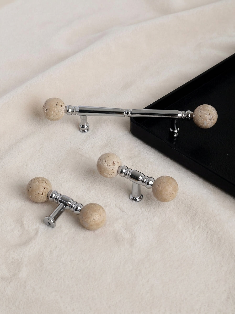 Short and long travertine ball chrome pulls side by side on fabric
