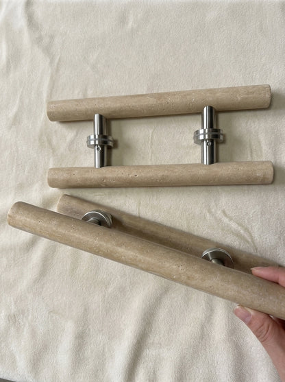 Beige travertine cylinder door pull held in hand showing 40 cm length and natural stone texture